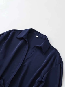 Close-up of the satin texture and collar detail of a navy blue long sleeve V-neck shirt