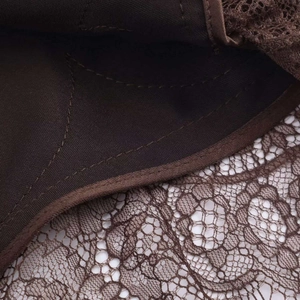 Détail de la dentelle marron à motifs floraux et des coutures précises sur la robe