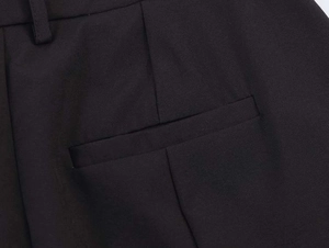 Detailed macro shot of black tailored trousers showing waistband loops and welt pocket