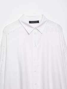 Detailed view of white cotton-linen shirt with elegant lace stitching and fringe sleeve accents