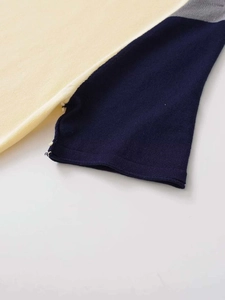 Close-up of tricolor stitching and fine knit texture on the color block sweater sleeve