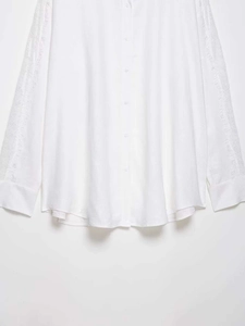 Close-up of white long sleeve blouse with lace embroidery detail and pleated texture