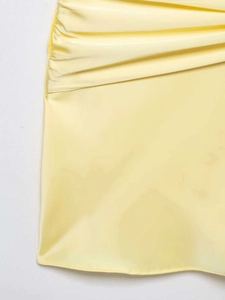Detail view of light yellow satin dress showing refined side ruching and silky texture
