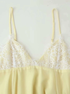 Detail of light yellow satin dress featuring delicate white eyelash lace patchwork trim