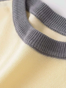 Detailed macro view showing the beige knit fabric and contrast grey ribbed neckline