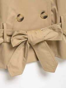 Close-up of khaki trench coat waist featuring double-breasted buttons and tied bow belt