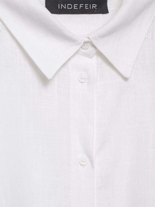 Detailed macro view of white cotton linen shirt with lace trim and brand neck label
