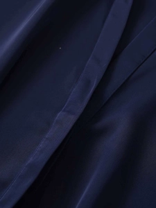 Close-up of high-quality navy blue V-neck shirt fabric showing detailed sewing and silk texture
