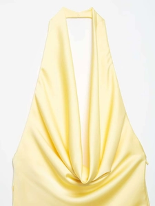 Detail of light yellow satin halter dress showing elegant draped neckline and silky texture