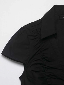 Detail view of the elegant black short sleeve shirt featuring ruffled pleats and V-neckline