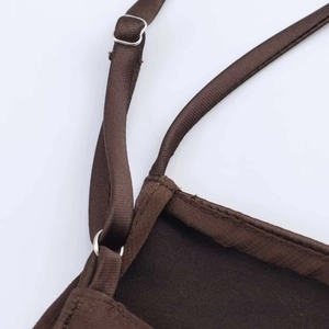 Détail de la fine bretelle réglable sur robe en satin marron avec curseur métallique