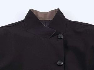 Detail of a black blazer collar with brown lining and decorative embossed buttons