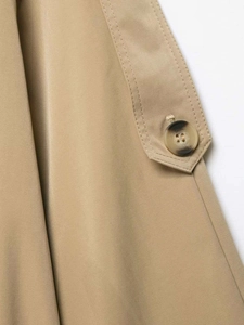 Detail of khaki trench coat featuring twill fabric texture and amber decorative button
