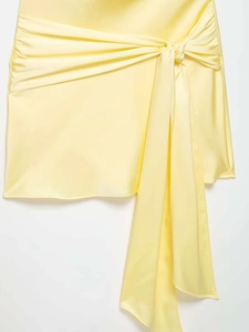 Detailed view of the yellow satin mini skirt featuring a knot waist and long flowing ties