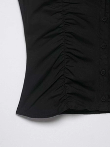 Detail view of black shirt with ruched side seam and matching circular buttons