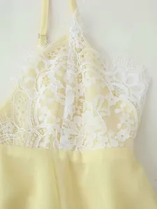 Detail of delicate white floral lace patchwork on a light yellow spaghetti strap dress