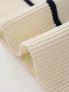 Close-up of ribbed knit fabric texture in cream white with navy blue stripe detail