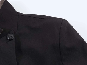 Detail of a black blazer featuring a sophisticated embossed crest button and premium fabric