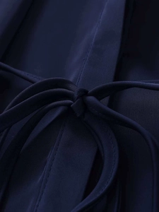 Detail of navy blue V-neck blouse showing smooth fabric texture and tied waist belt bow