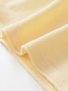 Detailed macro view of pale yellow knit fabric texture with ribbed hem finish