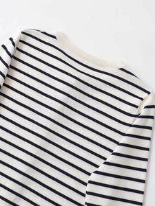 Close-up detail of the ribbed crew neck and black and white striped knit texture on a sweater