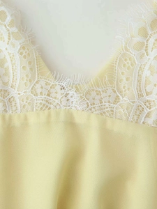 Detail shot of light yellow dress V-neckline with delicate white eyelash lace trim