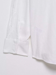 Detail of white cotton linen blouse cuff with double buttons and delicate lace embroidery