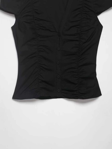 Detail of V-neckline on black short sleeve shirt with button-down and pleated texture