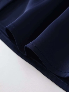 Detail of navy blue V-neck shirt fabric showing fine texture and hem stitching craftsmanship