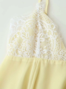 Detail of light yellow chiffon dress featuring intricate white floral lace and thin straps