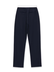 Detailed view of dark blue straight trousers with contrasting white waistband and rear pockets