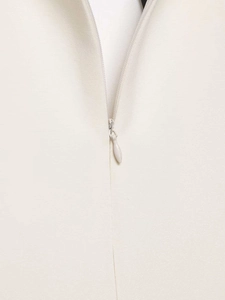Macro shot of the concealed zipper on the elegant off-white woven fabric of the dress