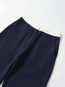 Detailed view of navy blue trouser waist with white contrast trim and side pocket