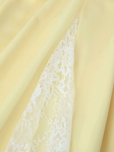 Detail of light yellow summer dress showing delicate white floral lace patchwork stitching