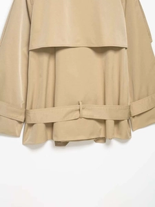 Detail of rain guard and waist belt loops on a khaki double-breasted trench coat