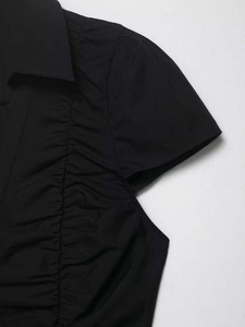Close-up of black short sleeve blouse featuring lapel collar and side pleated details