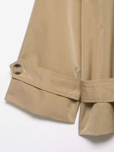 Detailed close-up of khaki trench coat sleeve with buckled cuff and marble-textured button