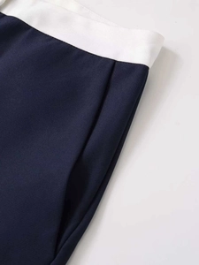 Detailed close-up of dark blue trousers with contrasting white waistband and side pocket