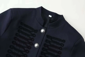 Detail of navy military jacket featuring stand collar and ornate silver metal buttons