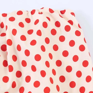 Detail view of red polka dots on beige fabric with elastic shirring for summer top