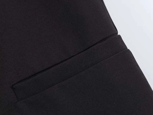Detail of a jetted pocket on a black blazer with precise stitching and flat texture