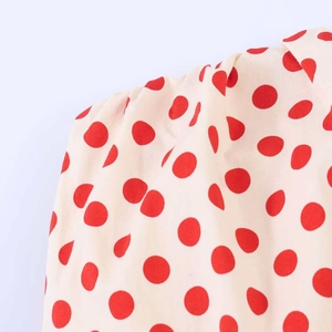 Detailed macro view of cream polka dot fabric with refined gathered shoulder stitching