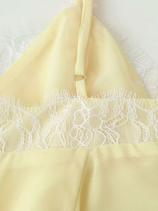 Close-up of delicate white floral lace trim on a light yellow summer camisole dress