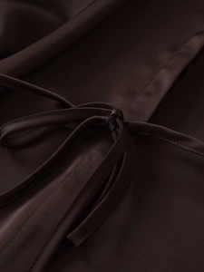 Detail of a dark brown satin shirt featuring a tied knot and smooth silk texture
