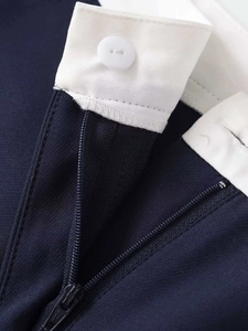 Close-up of contrast white waistband, white button and zipper on navy trousers