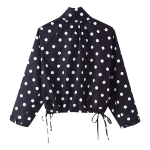 Detailed view of the pleated back design and polka dot fabric on the cropped jacket