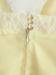 Macro detail of exquisite white lace trim and covered buttons on a yellow summer dress