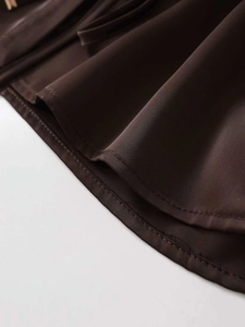 Detailed close-up of dark brown woven fabric with neat stitching and pleated design