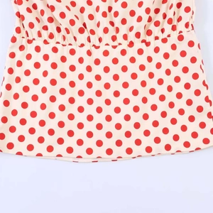 Detailed close-up of the elastic waist and red polka dot pattern on the white fabric