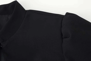 Macro detail of black short sleeve blazer showing stand collar and textured fabric